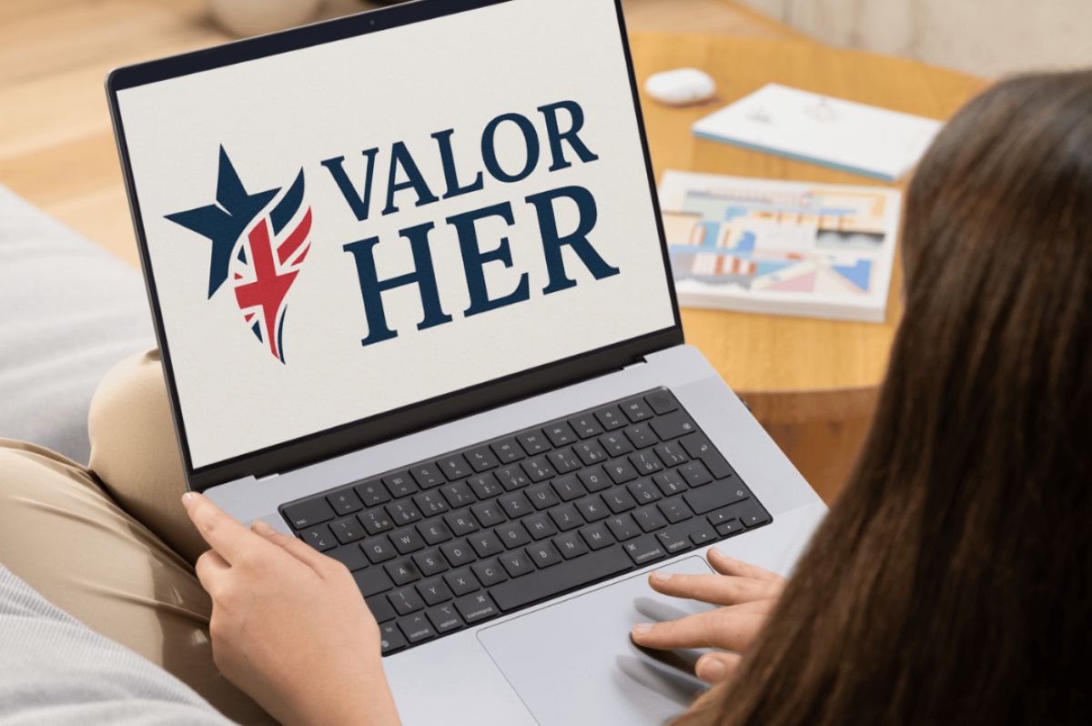 Woman sat using a laptop with Valor Her logo on the screen